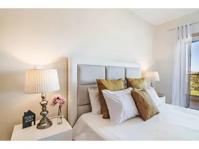 a bedroom with a white bed with a lamp and flowers at Apartment Loft 39 - Sunny Way by Interhome in Albufeira