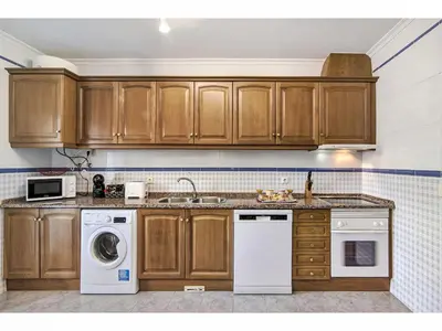 a kitchen with wooden cabinets and a washer and dryer at Apartment Manelito House - Sunny Way by Interhome in Albufeira