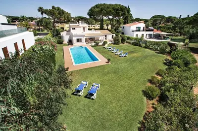 a villa with a swimming pool in front of a house at 4 Beds, Golf Views, optional pool heating in Vilamoura