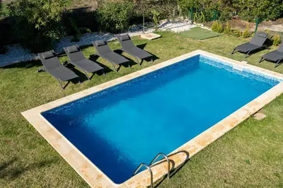 an empty swimming pool with chairs in a yard at Vitoria 7th hole by SAPvillas in Vilamoura