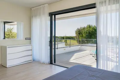 a bedroom with a large glass door leading to a balcony at Vitoria 7th hole by SAPvillas in Vilamoura