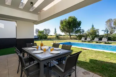 a patio with a table and chairs and a swimming pool at Vitoria 7th hole by SAPvillas in Vilamoura