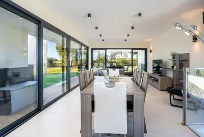a dining room with glass walls and a table and chairs at Vitoria 7th hole by SAPvillas in Vilamoura
