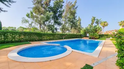 a swimming pool in a yard with trees at Golfview Apartment in Quarteira