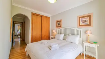 a bedroom with a white bed with two towels on it at Golfview Apartment in Quarteira