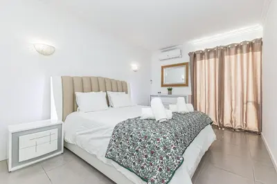 a bedroom with a large white bed and a window at Quiet & Sea in Albufeira