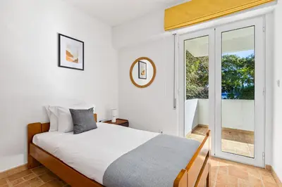 a bedroom with a bed and a large window at Bright 3BDR Vilamoura Retreat Flat by LovelyStay in Quarteira