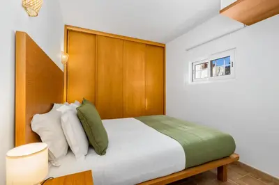 a bedroom with a large bed with a wooden headboard at Bright 3BDR Vilamoura Retreat Flat by LovelyStay in Quarteira