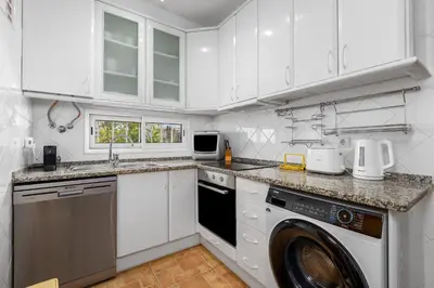 a kitchen with white cabinets and a washer at Bright 3BDR Vilamoura Retreat Flat by LovelyStay in Quarteira