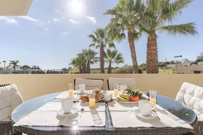 a table with a plate of food on a patio with palm trees at Palm Breeze Retreat in Albufeira w Pool and Balcony by Lisbeyond in Albufeira