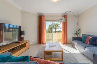 a living room with a couch and a tv at Palm Breeze Retreat in Albufeira w Pool and Balcony by Lisbeyond in Albufeira