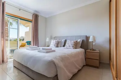 a white bedroom with a large bed and a window at Palm Breeze Retreat in Albufeira w Pool and Balcony by Lisbeyond in Albufeira