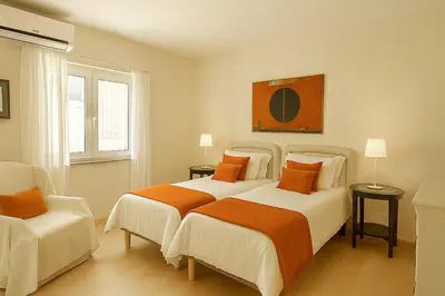 a bedroom with two beds and a chair at Villa Mar by Sunny Deluxe in Albufeira