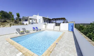 a villa with a swimming pool in front of a house at Monte Juntos in Guia
