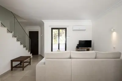 a white living room with a couch and a tv at Marina Búzios I & II - Vilamoura Marina by HD in Vilamoura