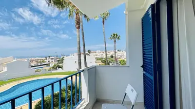 a balcony with a view of a pool and palm trees at Jardim da Oura by Check-in, Portugal in Albufeira