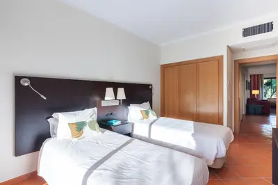 two beds in a hotel room with white sheets at F5 Vila Sol G Pool & Golf in Vilamoura in Quarteira