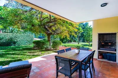a patio with a wooden table and chairs at F5 Vila Sol AI Pool & Golf in Vilamoura in Quarteira