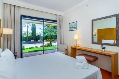 a hotel room with a bed and a desk and a window at F5 Vila Sol AI Pool & Golf in Vilamoura in Quarteira