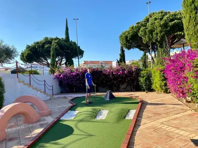 a man is playing golf on a miniature golf course at Solar Vilamoura Relaxing Apartment Stay in Quarteira