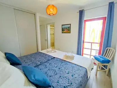 a bedroom with a blue bed and a window at Sunny Condo facing the pool by Algarve Dream Holidays in Quarteira