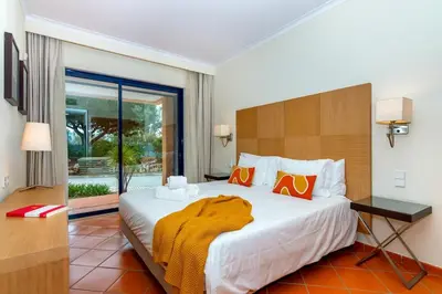 a bedroom with a large white bed with orange pillows at F5 Vila Sol AP Pool & Golf in Vilamoura in Quarteira
