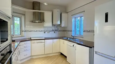 a white kitchen with white cabinets and windows at Pinheiro Manso by Check-in Portugal in Albufeira