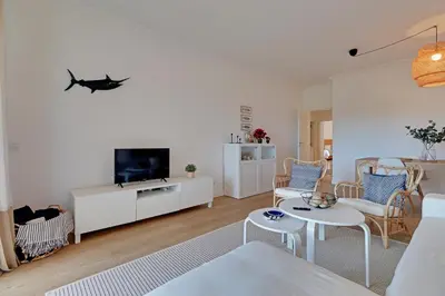 a living room with white furniture and a flat screen tv at Las Palmeiras Vilamoura in Quarteira