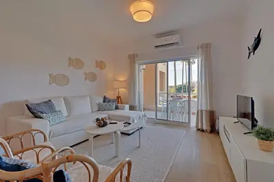 a living room with a white couch and a tv at Las Palmeiras Vilamoura in Quarteira