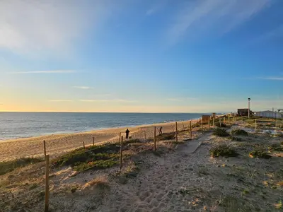a person walking down a sandy beach next to the ocean at Blife Josya private apartment at Faro beach in Faro