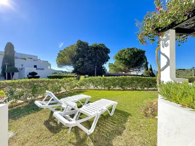 two white chairs sitting on the grass in a yard at Albufeira Balaia Golf Vilage 8 With Pool by Homing in Albufeira