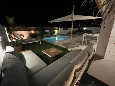 a swimming pool at night with a couch and an umbrella at Casa Alegria in Tunes