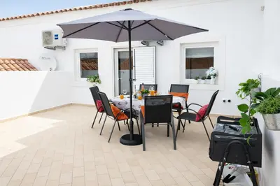 a table and chairs with an umbrella on a patio at Varanda da Baixa, cosy apartment, top location, private terrace, barbecue, AC and Wi-Fi in Faro