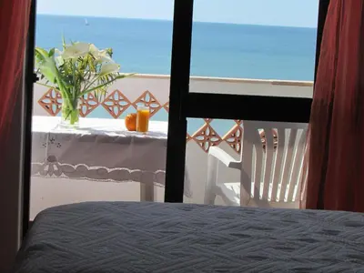 a table with a vase of flowers on a balcony with the ocean at Apartment NASCER-DO-SOL by Interhome in Quarteira