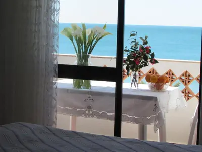a table with a vase of flowers and a view of the ocean at Apartment NASCER-DO-SOL by Interhome in Quarteira