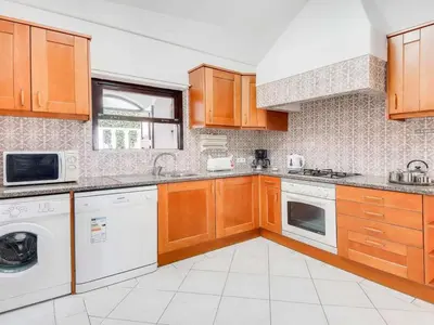 a kitchen with wooden cabinets and a washer and dryer at Holiday Home Chalet Villa Brigida mit privatem Pool by Interhome in Albufeira