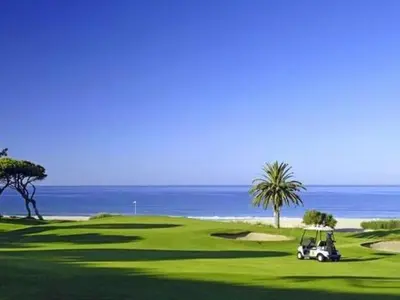 a golf cart on a green with the ocean in the background at Apartment Wohnung mit Terrasse by Interhome in Albufeira