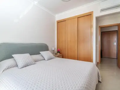 a bedroom with a white bed and a wooden cabinet at Apartment Elena 2 mit Blick auf das Wasser by Interhome in Albufeira