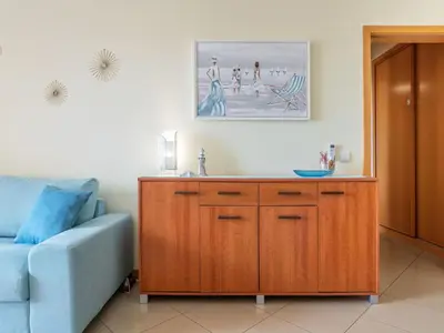 a living room with a blue couch and a wooden cabinet at Apartment Elena 1 mit Blick auf das Wasser by Interhome in Albufeira