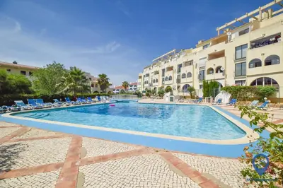 a swimming pool in a resort with chairs and buildings at Vitoria 1 by MTPhomes in Albufeira