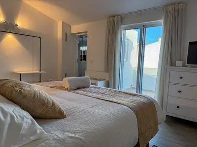 a bedroom with a large white bed with a balcony at Villa Nova En-suite luxury, private pool, sea view in Albufeira