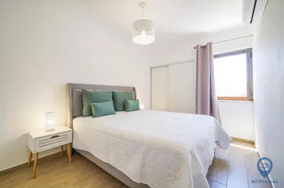 a white bedroom with a bed and a window at Bordalo by MTPhomes in Albufeira