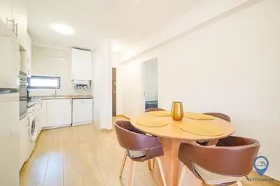 a kitchen and dining room with a wooden table and chairs at Bordalo by MTPhomes in Albufeira