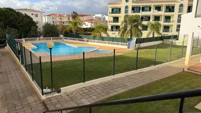 a fence around a swimming pool in a city at Maple Apartment in Albufeira