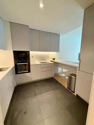 a white kitchen with white cabinets and a counter at Horizon Sand Beachfront apartment - Pool View, Quarteira in Bicas