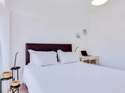 a bedroom with a white bed and a laptop on a desk at AL - Apartamento Wave 7 in Quarteira