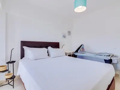 a bedroom with a large white bed and a table at AL - Apartamento Wave 7 in Quarteira