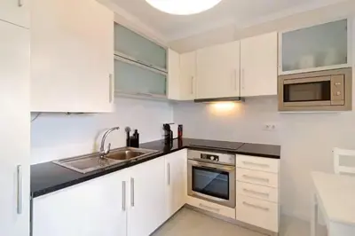 a kitchen with white cabinets and a sink at Apartment Jardins da Falesia in Roja- Pé