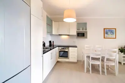 a kitchen with white cabinets and a table and chairs at Apartment Jardins da Falesia in Roja- Pé