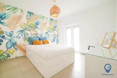 a bedroom with a bed with a tropical wallpaper at Palmeiras by MTPhomes in Albufeira